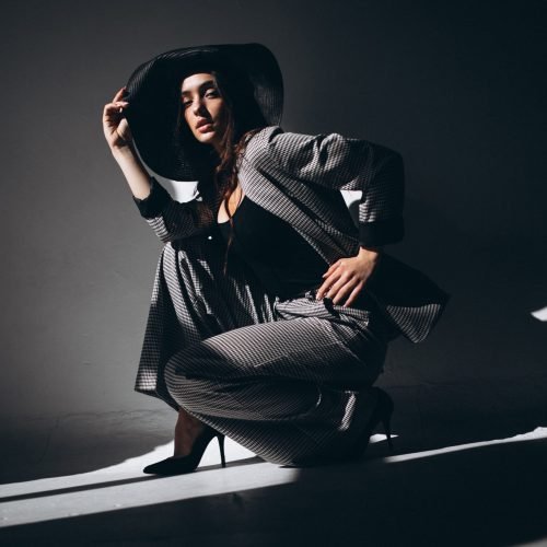 Woman model in a business suit wearing a hat in a studio